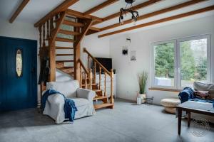 a living room with a wooden staircase and a chair at Gawra nad potokiem in Bystre