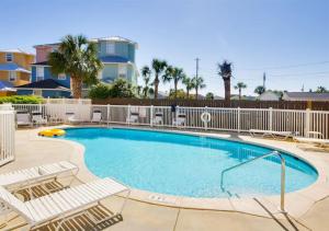 a large swimming pool with chairs and a fence at Emerald Coast Cabana in Panama City Beach