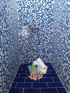 a blue tiled bathroom with a bouquet of flowers on the floor at Valantas Garden Suite in Lardos