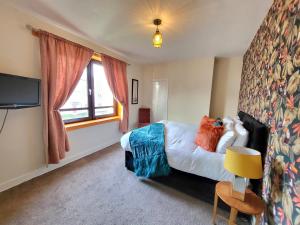 アバディーンにある3 Bedroom Aprtmt at Sensational Stay Serviced Accommodation Aberdeen- Froghall Avenueのベッドとテレビ付きのホテルルーム