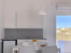 cocina con armarios blancos, mesa y sillas en Palm Suite Yellow en Porto Heli