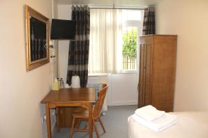 a room with a table and a bed and a window at The Dial House Guest House in Oxford