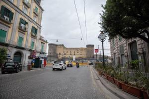 una calle de la ciudad con coches y un castillo en el fondo en B&B DORIA, en Nápoles