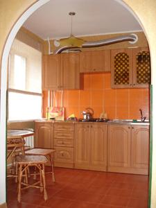 a kitchen with wooden cabinets and a table and a sink at Apartments Zatyshok in Chernihiv