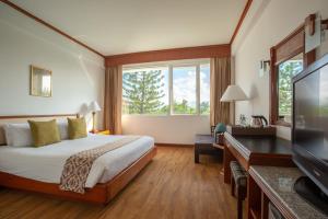 a hotel room with a bed and a flat screen tv at Centara Life Hotel Mae Sot in Mae Sot