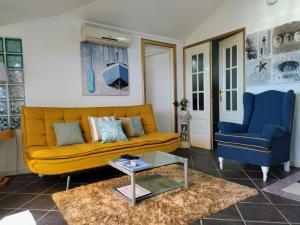 a living room with a yellow couch and two blue chairs at ATTIC BAY - Cozy Stay with Sea View in Câmara de Lobos +66 photos