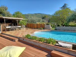un patio trasero con piscina y terraza de madera en Lou Viei Jas, en Figanières