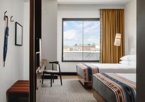 Cette chambre comprend un lit, un bureau et une fenêtre. dans l'établissement Hotel Tupelo, a Wyndham Hotel, à Tupelo