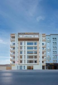 a large white apartment building with a parking lot at Centara Life Muscat Dunes Hotel in Muscat