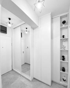 Dieses weiße Zimmer verfügt über einen Spiegel und einen Flur. in der Unterkunft Apartman Barocco in Trebinje