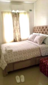 a bedroom with a large bed with two windows at Cozy Vacation House in Guimaras in Guimaras