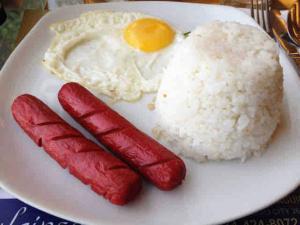 a plate of food with eggs and sausages and rice at Cozy Vacation House in Guimaras in Guimaras