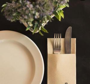 a fork and knife in a paper napkin next to a plate at Casa rural luciano in Malagón