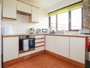 una cucina con mobili bianchi e una stufa di Kestrel Corner a Lanivet Altre 7 foto
