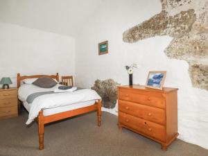 a bedroom with a bed and a wooden dresser at Foxes in Lanivet