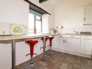 a kitchen with red stools in a kitchen with white cabinets at Ravens Croft in Lanivet