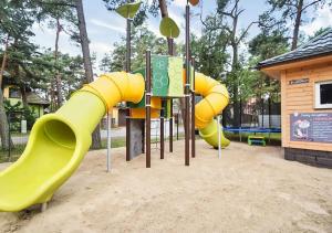 un parque infantil con tobogán amarillo en Kolorowe Domki en Pobierowo