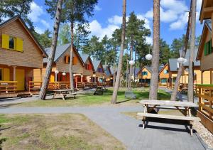 un parc avec des bancs, des arbres et des bâtiments dans l'établissement Kolorowe Domki, à Pobierowo