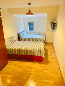 2 camas en una habitación con suelo de madera en QuickSpaces Alexandra Apartments, en Mánchester