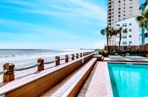 a swimming pool next to a beach next to a building at 1109 Waters Edge Resort condo in Myrtle Beach