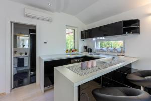 a kitchen with a white counter top and black cabinets at Villa M in Dramalj