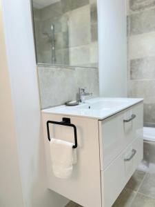 ein weißes Badezimmer mit einem Waschbecken und einem Spiegel in der Unterkunft Villa Cocody in Bandol