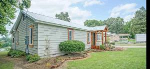 a small white house with a yard at Ledgerock lake house! Boat included march-October,outside bar, Pool table,family fun center in Hot Springs