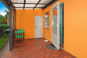 an orange house with a chair and an open door at Bungalow Am Spreeufer Lübben - DBS05100b-B in Lübben