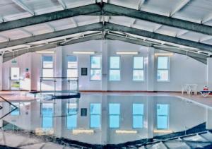 a swimming pool in a building with a reflection in the water at Luxury 3 bedroom caravan between Perranporth and Newquay, Cornwall in Newquay