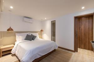 a bedroom with a white bed and a wooden door at Villaz Luxury Vacation Homes in Medellín