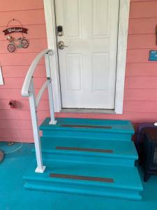 a front door of a pink house with blue stairs at Coastal Cottage Bay House in Palacios