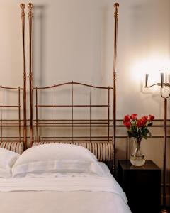 Maison Matilda - Luxury Rooms & Breakfast في تريفيزو: سرير بإطار معدني و مزهرية ورد احمر