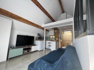 sala de estar con sofá azul y TV en CosySmartStudio, en Montigny-le-Bretonneux