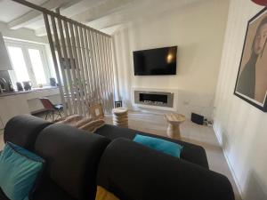 ミラノにあるBrera Charme Suiteのリビングルーム(黒いソファ、テレビ付)