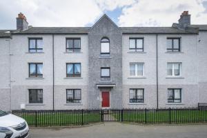 an apartment building with a red door at 3 Bedroom Aprtmt at Sensational Stay Serviced Accommodation Aberdeen- Froghall Avenue in Aberdeen