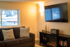 a living room with a couch and a flat screen tv at Clipperton Suite by Revelstoke Vacations in Revelstoke