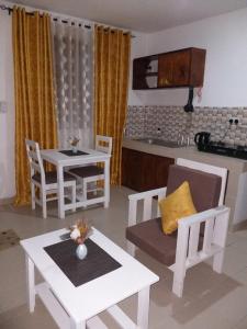 a kitchen and living room with white tables and chairs at Hyven's Apartments in Mtwapa