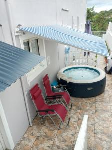 a hot tub on a patio with chairs and a roof at VILLA AU COEUR DE LA MARMITE in Sainte-Marie