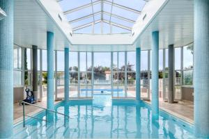 une grande piscine avec colonnes bleues et fenêtres dans l'établissement NATICE Bel appartement dans résidence privée, à Saint-Martin-de-Ré
