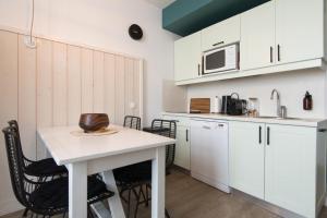 - une cuisine avec des placards blancs, une table et un four micro-ondes dans l'établissement NATICE Bel appartement dans résidence privée, à Saint-Martin-de-Ré