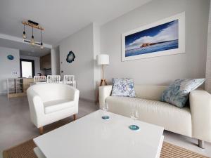 een woonkamer met een witte bank en een stoel bij SUNSET WAVES sea & sky apartment in Benidorm