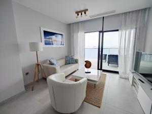 a white living room with a couch and a tv at SUNSET WAVES sea & sky apartment in Benidorm