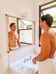 a man standing in front of a bathroom mirror at Base Airlie Beach in Airlie Beach