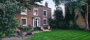 una grande casa in mattoni con un cortile con un prato di Manor House of Cheshunt- Historic Villa a Cheshunt