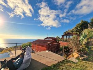 twee personen op de patio van een huis bij Madeira Sunset Cottage - Nature Retreat in Ponta do Pargo