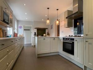 een grote witte keuken met witte kasten en apparaten bij Manor House of Cheshunt- Historic Villa in Cheshunt