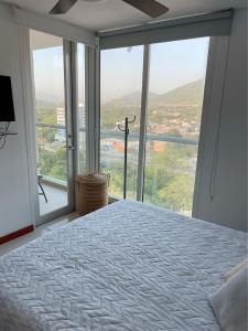 um quarto com uma cama e uma grande janela em Apartamento Condominio Zazue Santa Marta em Santa Marta