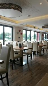 un comedor con mesas, sillas y ventanas en Alpenflair Hotel, en Buchloe