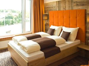 a bedroom with a large bed with a large window at Alpenflair Hotel in Buchloe