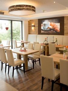 a restaurant with tables and chairs and a painting on the wall at Alpenflair Hotel in Buchloe